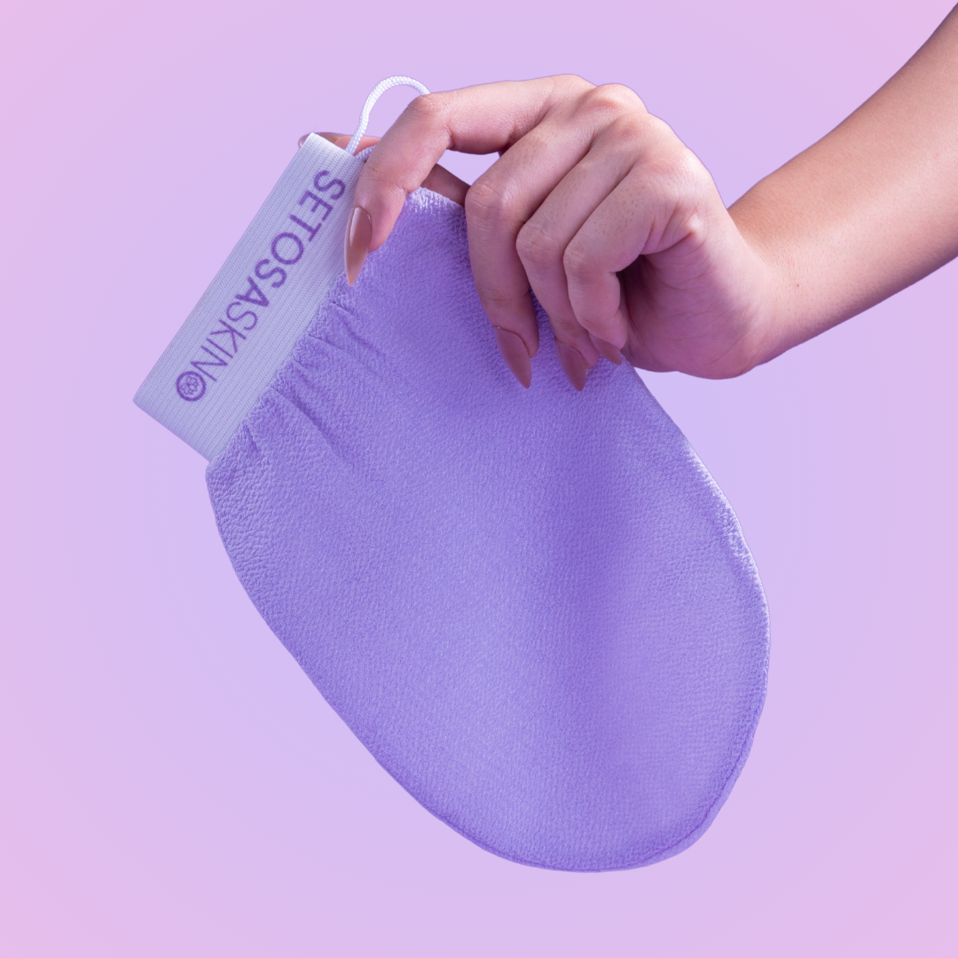 Purple exfoliating glove held by a hand with Setosa Skin tag